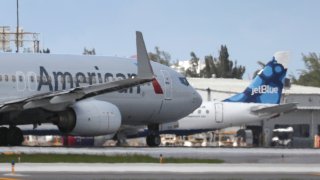 FORT LAUDERDALE, FLORIDA - JULY 16: An American Airlines plane takes off near a parked JetBlue plane at the Fort Lauderdale-Hollywood International Airport on July 16, 2020 in Fort Lauderdale, Florida. JetBlue Airways and American Airlines Group announced they will be creating an alliance between the two companies.
