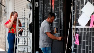 Una mujer habla por teléfono mientras un hombre remoza su negocio