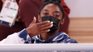 Simone Biles, wearing a mask, blows a kiss