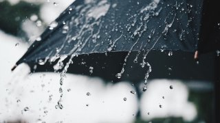 An open umbrella with rain overhead.