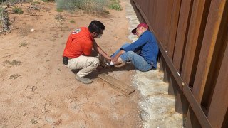 Paramédico auxilia a migrante que cayó del muro fronterizo