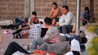 Fotografía de varios hombre y un niño que forman parte de un grupo de migrantes en una bodega