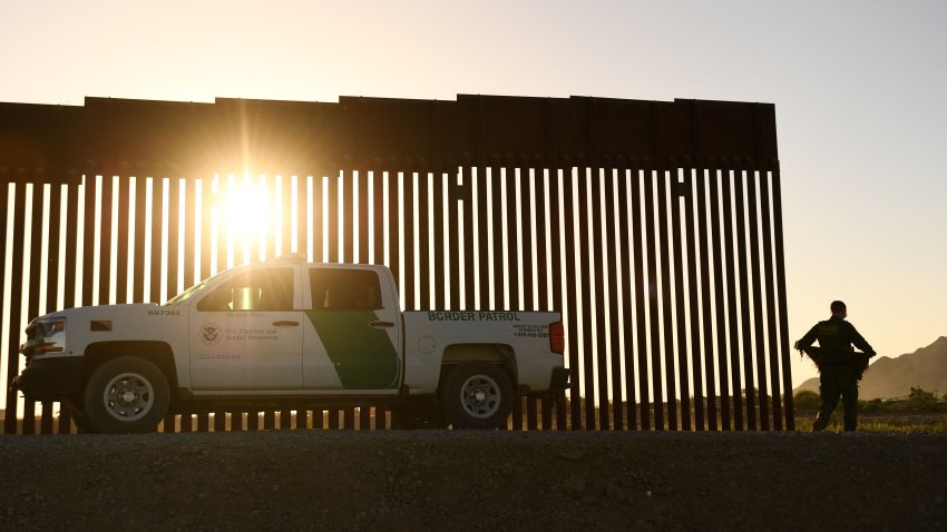 A Border Patrol agent walks between a gap along the border wall between the US and Mexico in Yuma, Arizona on June 1, 2022. – In May, US Secretary of Homeland Security Alejandro Mayorkas authorized US Customs and Border Protection (CBP) to use some existing DHS appropriations to close gaps in the Yuma Sector border bollard barrier fence as migrants seeking asylum cross the border and Title 42 restrictions on immigration continue, while DHS also said in a statement it calls on Congress to cancel remaining appropriations for barrier system construction and instead fund “smart border security” measures. (Photo by Patrick T. FALLON / AFP) (Photo by PATRICK T. FALLON/AFP via Getty Images)