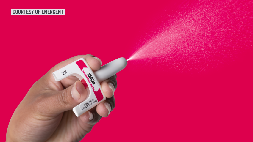 Hand spraying Narcan over red background