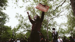 Un manifestante levanta una pancarta en la que se lee «Viva Palestina» en el campus después de que la policía declarara que la manifestación era una concentración ilegal en los terrenos de la Universidad de Virginia el 4 de mayo de 2024 en Charlottesville.