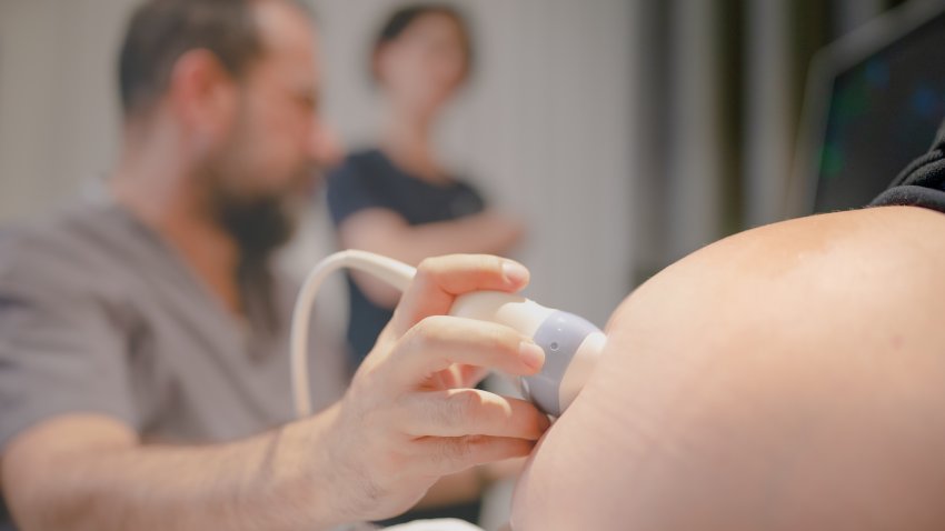 Gynecologist using ultrasound scanner while examining female patient