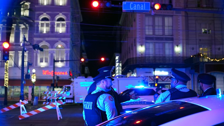 Police officers stand near the scene where a vehicle drove into a crowd on New Orleans' Canal and Bourbon streets, Wednesday, Jan. 1, 2025.